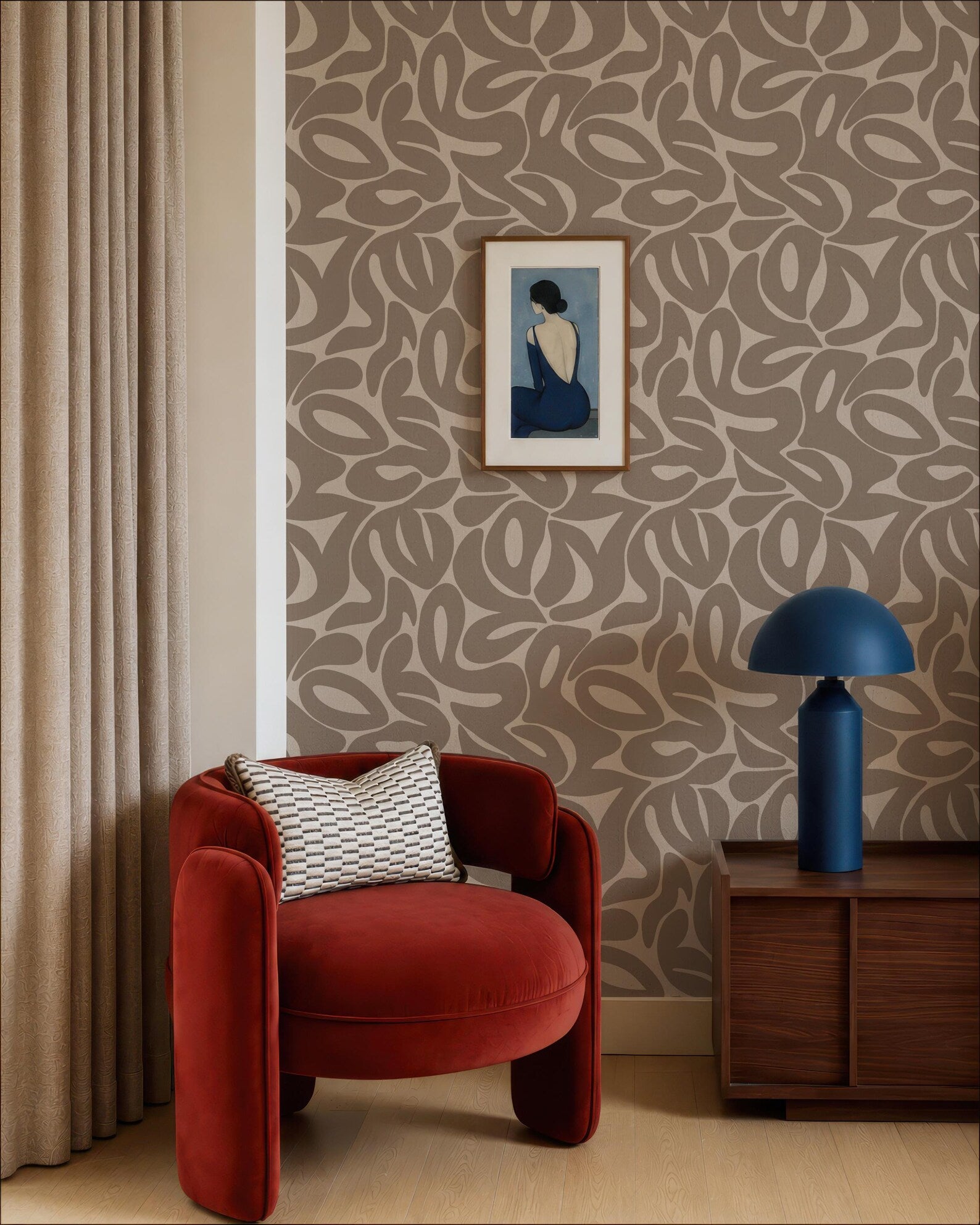 a modern living room with a red armchair, a wooden side table with a blue lamp, and a framed artwork on the wall.