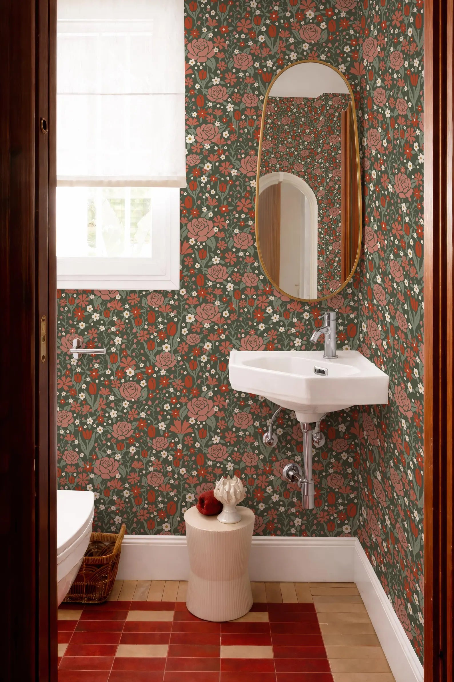 a bathroom with a floral wallpaper, a white sink, and a round mirror. The bathroom has a red and white checkered floor and a small stool in front of the sink.
