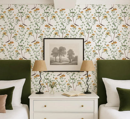 a bedroom with a white dresser, two green headboards, and a framed landscape painting above the dresser. The room has a floral wallpaper pattern and a white bed with a green headboard. There are two lamps on the dresser, and a book is placed on the dresser.