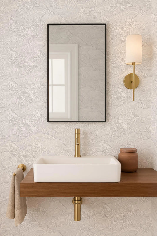 a modern bathroom with a white rectangular sink, a gold faucet, and a black framed mirror above it. The sink is placed on a wooden shelf, and there is a small brown vase on the shelf as well. The bathroom has a minimalist and elegant design, with a white and gold color scheme.