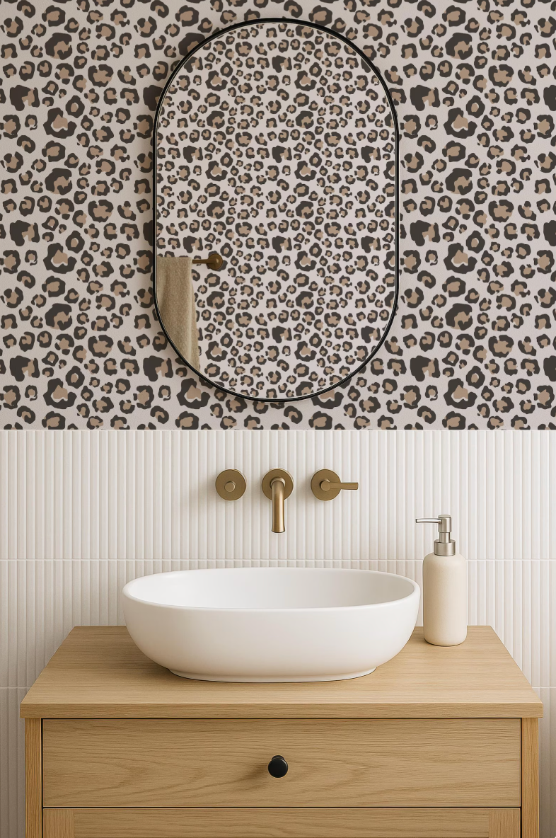 a bathroom with a white oval-shaped sink, a mirror with a leopard print frame, and a wooden vanity with a white soap dispenser.