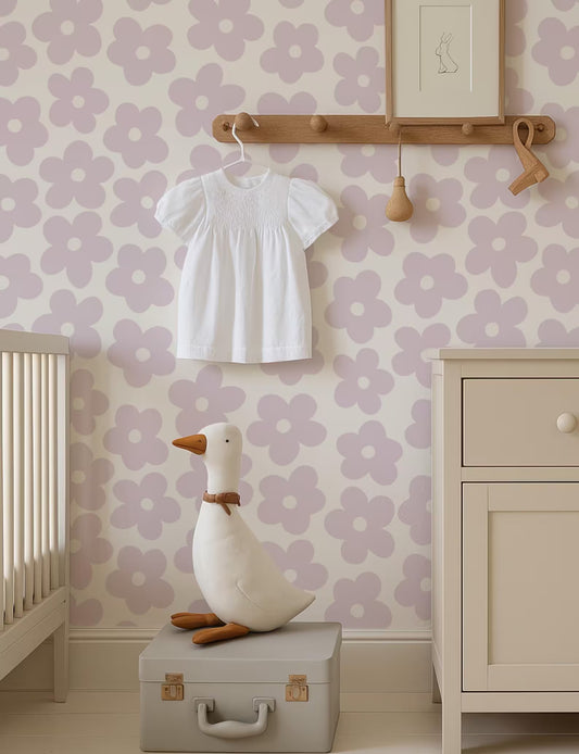 a nursery room with a white dress hanging on a wooden hanger, a stuffed duck sitting on a suitcase, and a wooden shelf with a picture frame. The walls are decorated with a floral pattern, and the room has a minimalist and clean design.