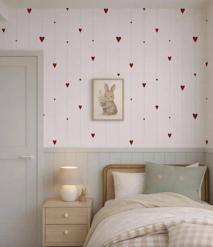 a cozy bedroom with a bed, nightstand, and a framed picture of a rabbit on the wall. The wall is decorated with red heart-shaped stickers, creating a cheerful and playful atmosphere.
