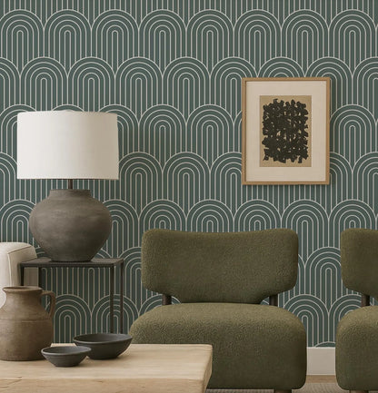 a modern living room with a green armchair, a wooden coffee table, and a lamp. The wall behind the furniture has a repeating pattern of arches in shades of green and blue, creating a visually striking backdrop. A framed abstract artwork is also present in the room, adding an artistic touch to the space.