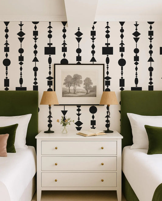 a bedroom with a white dresser, two green headboards, and a framed landscape painting on the wall. The room has a modern and stylish design with a black and white geometric pattern on the wall.