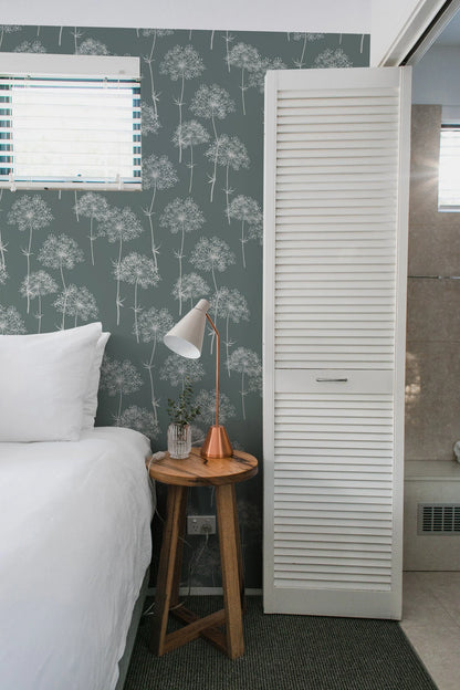 a cozy bedroom with a bed, a nightstand, and a white door with a window. The room has a green and white patterned wallpaper, and the bed is neatly made with white linens.