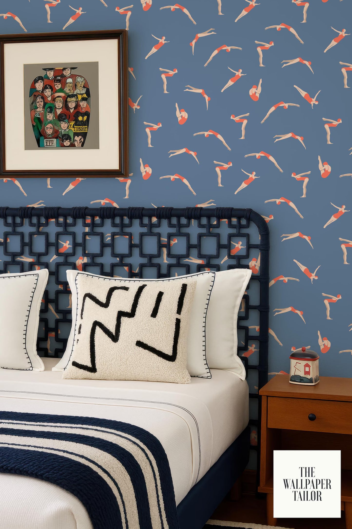 a bedroom with a blue and white color scheme, a black headboard, and a patterned wallpaper. There is a framed picture on the wall above the bed, and a small wooden nightstand next to the bed.