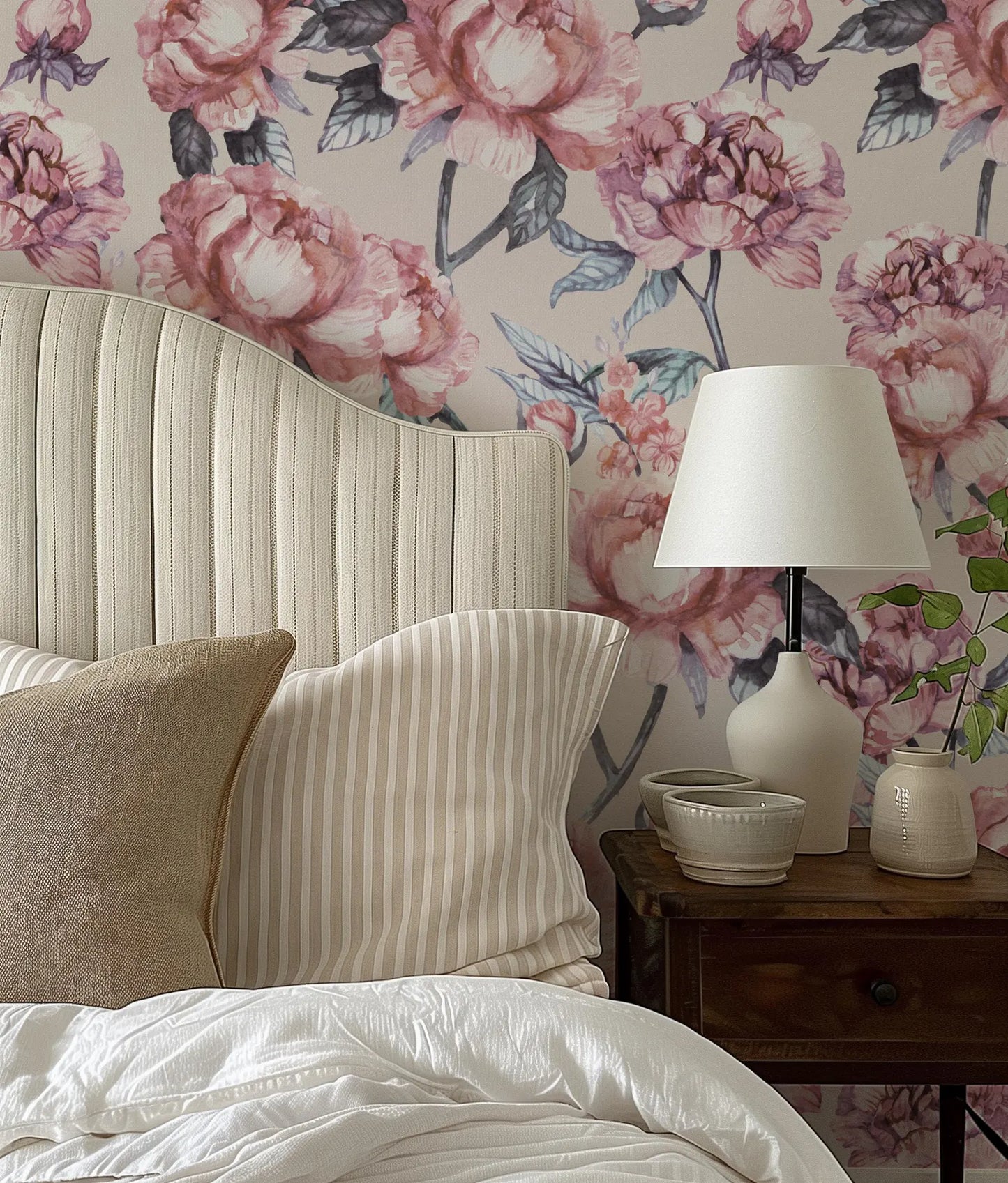a bedroom with a white bed, a wooden nightstand with a lamp, and a floral wallpaper.