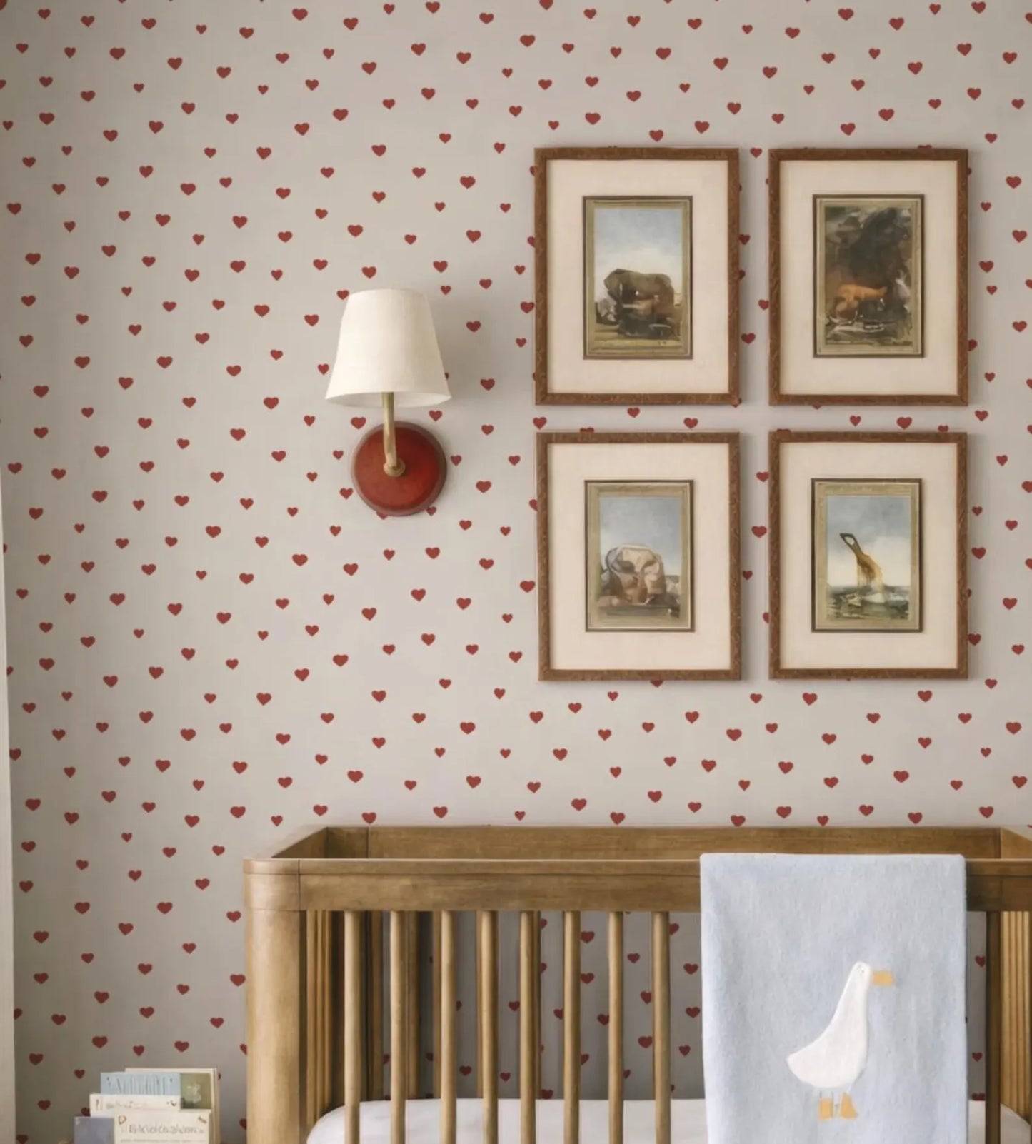 a cozy nursery room with a wooden crib, a wallpapered wall, and four framed pictures of animals.