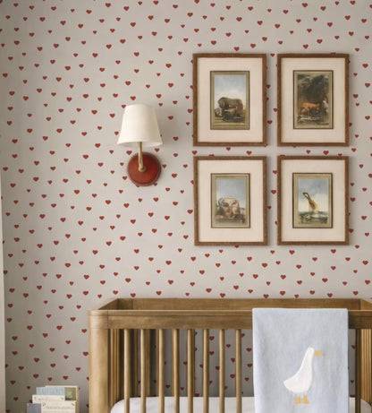 a cozy nursery room with a wooden crib, a wallpapered wall, and four framed pictures of animals.