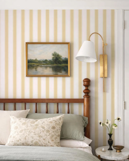 a bedroom with a wooden headboard, a framed landscape painting on the wall, and a lamp on the wall.