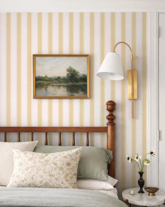 a bedroom with a wooden headboard, a framed landscape painting on the wall, and a lamp on the wall.