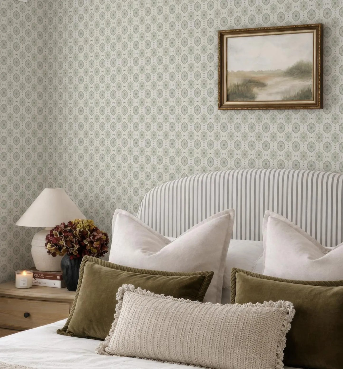a cozy bedroom with a striped headboard, a framed landscape painting on the wall, and a bed with a white and green striped comforter and pillows.