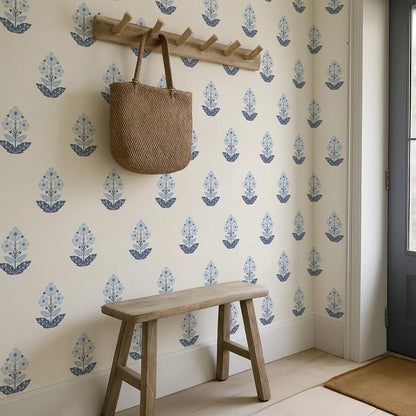 a wooden bench with a woven bag hanging on a wall with a repeating floral pattern.