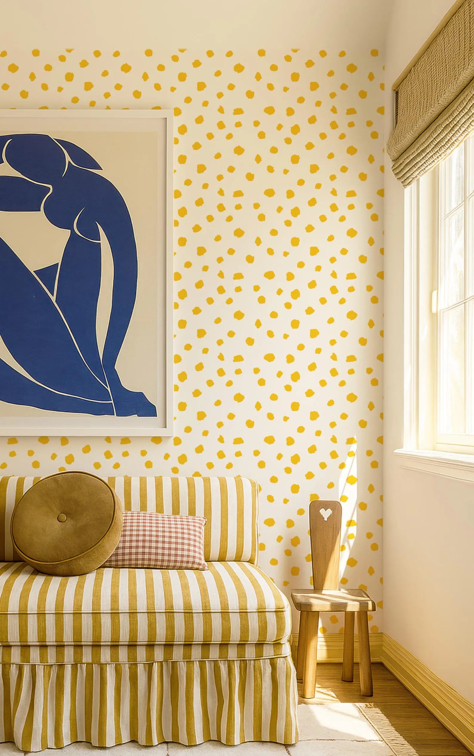 a cozy living room with a yellow and white striped sofa, a wooden chair, and a framed artwork on the wall. The room has a warm and inviting atmosphere, with the yellow and white polka dot wallpaper adding a playful touch.