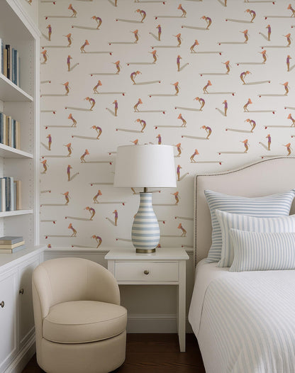 a cozy bedroom with a white bed, a beige armchair, and a white nightstand with a lamp. The walls are covered in a patterned wallpaper with various cartoon-like figures, creating a playful and vibrant atmosphere.