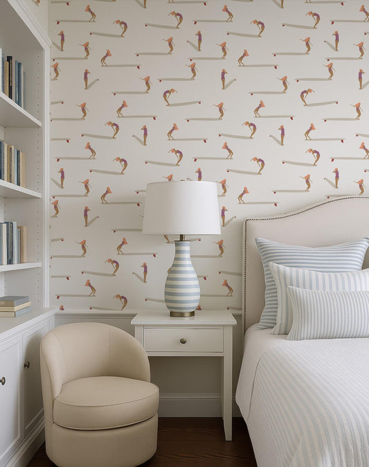 a cozy bedroom with a white bed, a beige armchair, and a white nightstand with a lamp. The walls are covered in a patterned wallpaper with various cartoon-like figures, creating a playful and vibrant atmosphere.