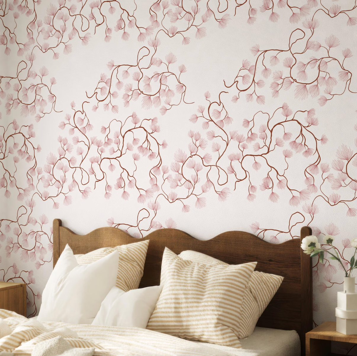 a bedroom with a wooden headboard and a bed covered in white and beige striped pillows. The wall behind the bed has a floral pattern in shades of pink and white.
