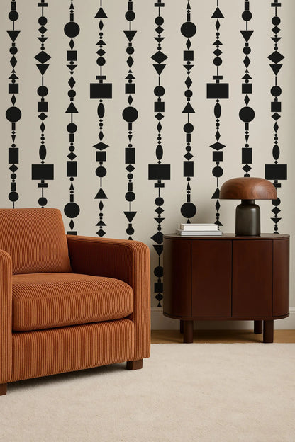 a modern living room with a brown armchair, a wooden side table, and a lamp on the table. The wall behind the furniture has a repeating pattern of black geometric shapes, creating a bold and contemporary design.