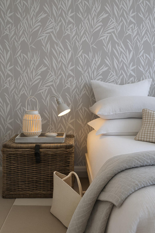 a cozy bedroom scene with a bed, a wicker chest, and a lamp on a nightstand. The bed is adorned with white pillows and a gray blanket, creating a serene and inviting atmosphere. The wicker chest adds a rustic touch to the room, while the lamp provides a warm and inviting glow. The overall scene conveys a sense of comfort and relaxation.