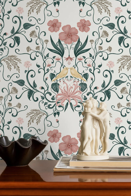 a decorative wall with a floral pattern, a white statue of two figures, and a black bowl on a wooden surface.