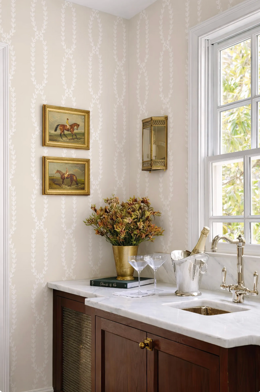a well-decorated kitchen with a white countertop, a vase of flowers, and a wine glass holder. The kitchen has a window that provides natural light, and there are two framed pictures on the wall.