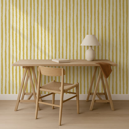 a wooden desk with a lamp and a chair, set against a striped yellow and white wall.