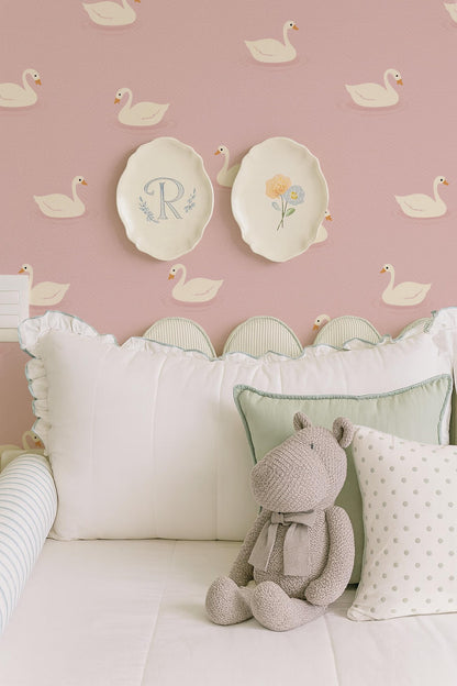 a cozy bedroom scene with a plush stuffed animal, a white bed with decorative pillows, and a wall with a repeating pattern of white swans.