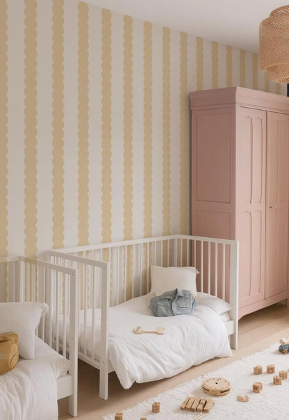 a cozy and well-organized nursery room with a white crib, a pink armoire, and a yellow and white striped wallpaper.
