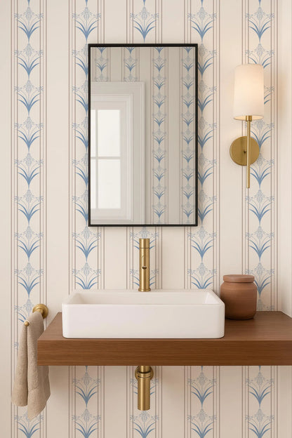 a bathroom with a white rectangular sink, a mirror above it, and a wooden shelf below the sink. The wall behind the sink has a blue and white patterned wallpaper.