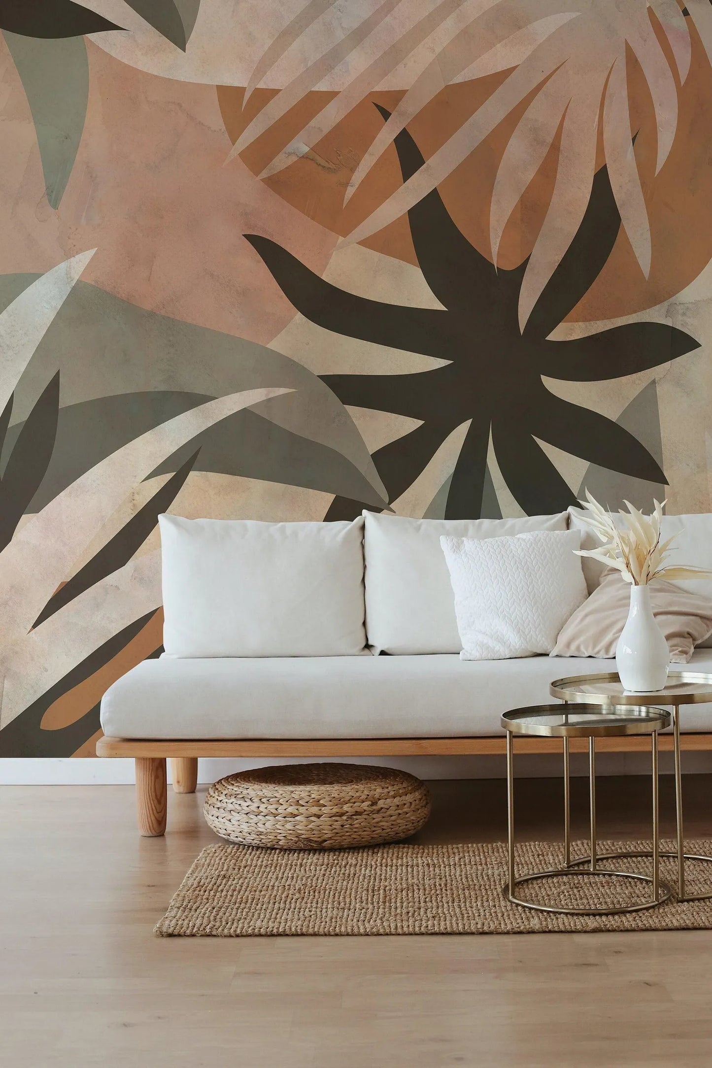 a modern living room with a white sofa, a woven rug, and a coffee table with a vase of flowers. The wall behind the sofa has a large abstract mural in shades of orange and green.