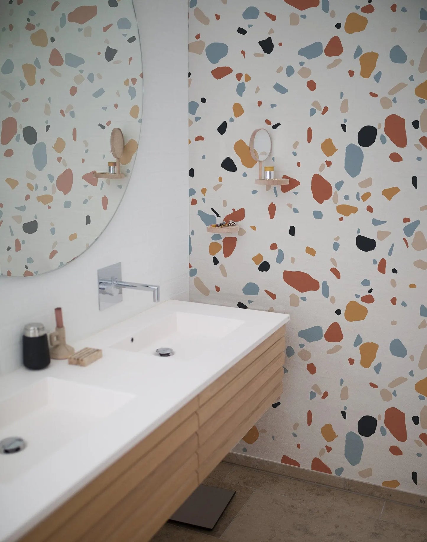 a modern bathroom with a large mirror, a double sink vanity, and a colorful, speckled wall design.