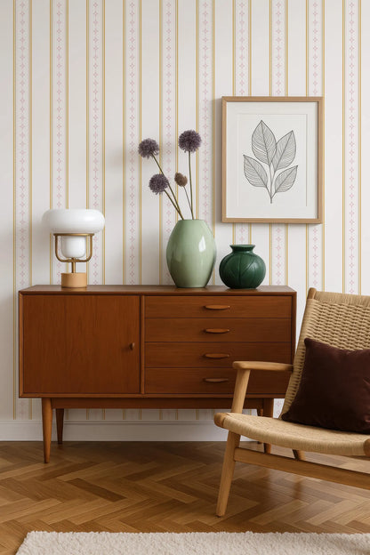 a cozy living room with a wooden sideboard, a woven chair, and a framed artwork on the wall. The sideboard has a lamp and a vase with purple flowers on top. The chair has a brown pillow on it. The artwork on the wall is a simple line drawing of a leaf and a flower.