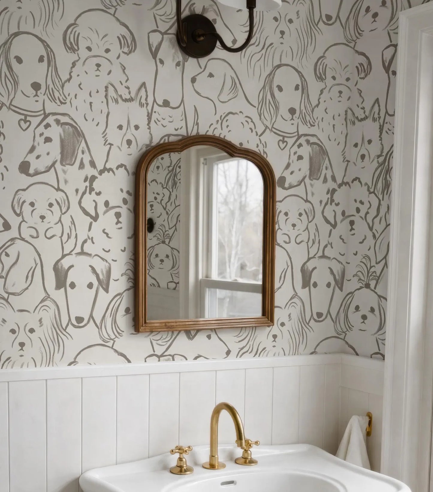 a bathroom with a white sink and a gold faucet, and a mirror above it. The wall behind the sink has a repeating pattern of dog faces, creating a playful and whimsical atmosphere.