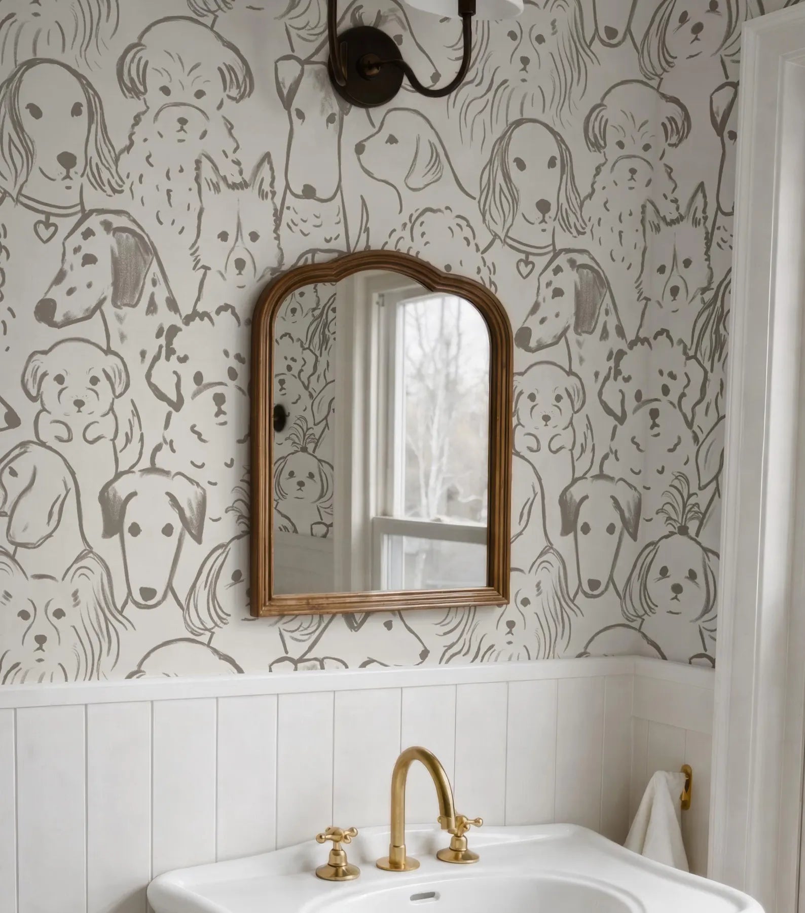 a bathroom with a white sink and a gold faucet, and a mirror above it. The wall behind the sink has a repeating pattern of dog faces, creating a playful and whimsical atmosphere.