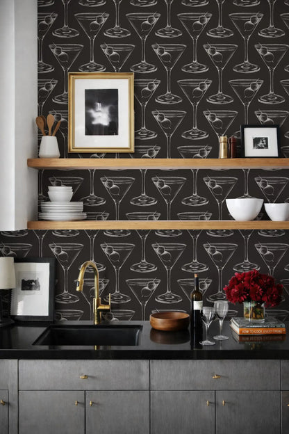 a kitchen with a black and white patterned wallpaper, a black countertop, and a shelf with various kitchen items such as a bowl, a wine bottle, and a vase.