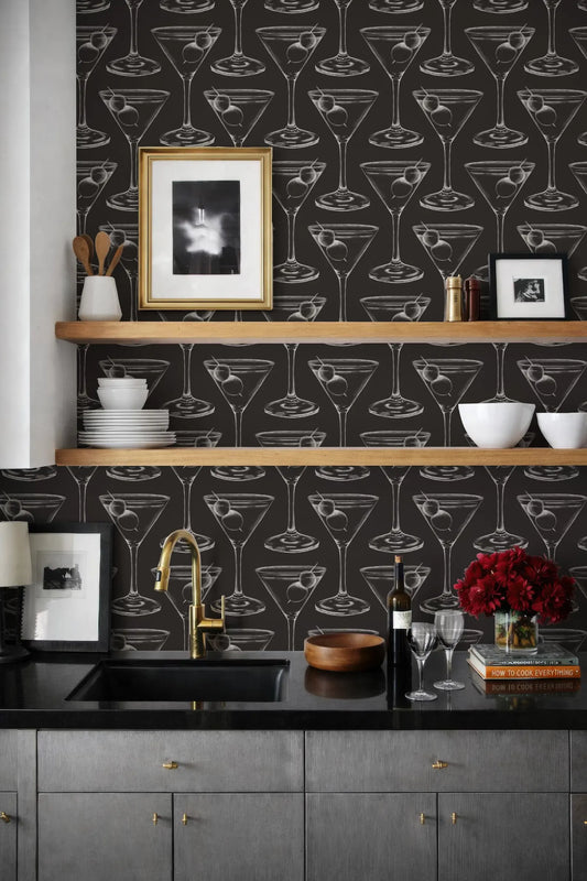 a kitchen with a black and white patterned wallpaper, a black countertop, and a shelf with various kitchen items such as a bowl, a wine bottle, and a vase.