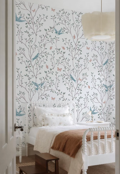 a bedroom with a white bed frame and a white headboard. The wall behind the bed has a floral wallpaper with a tree design and birds. The room has a white color scheme, and there is a white lamp hanging from the ceiling.