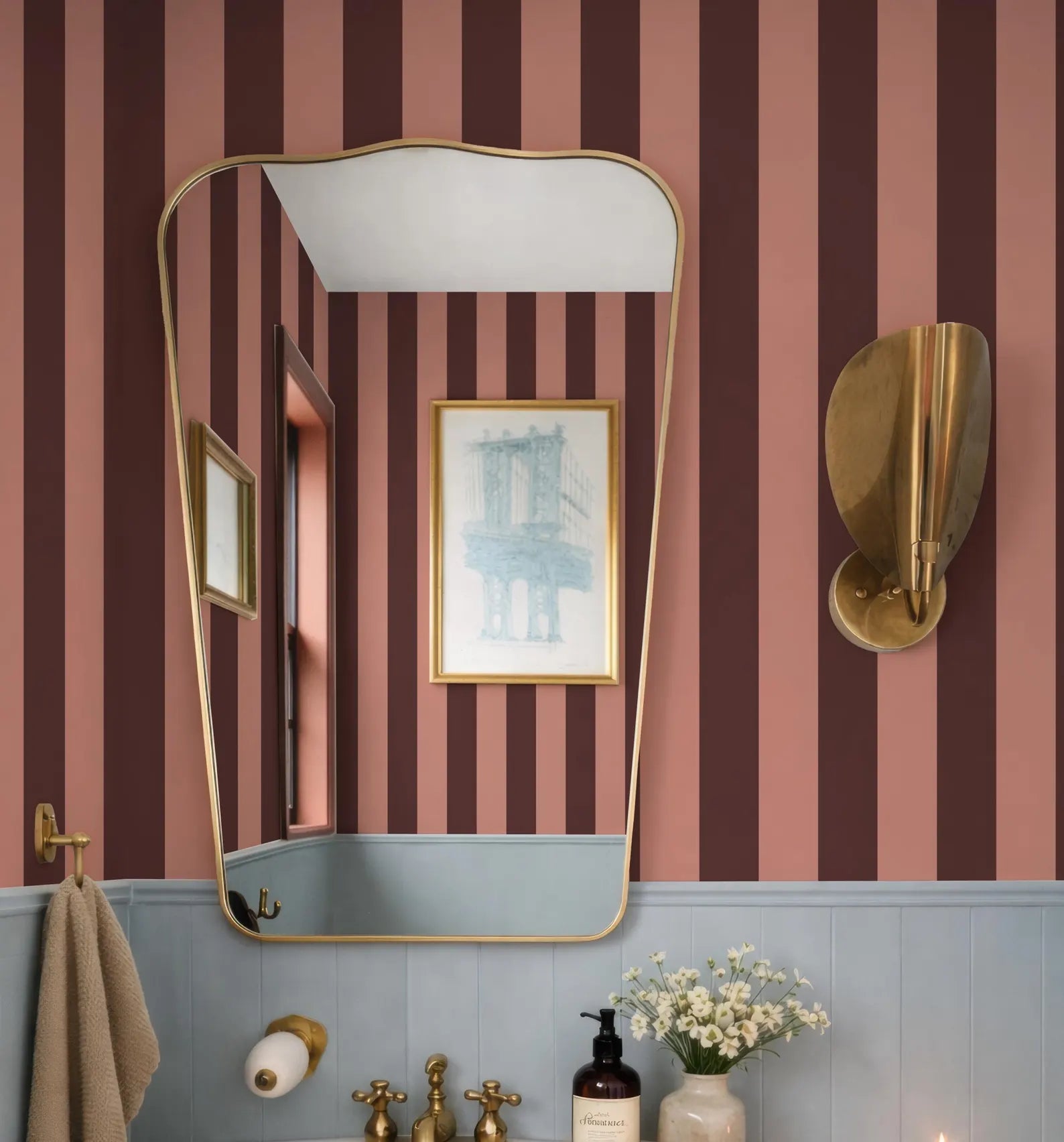 a bathroom with a pink and black striped wallpaper, a large mirror, and a gold-framed picture on the wall.