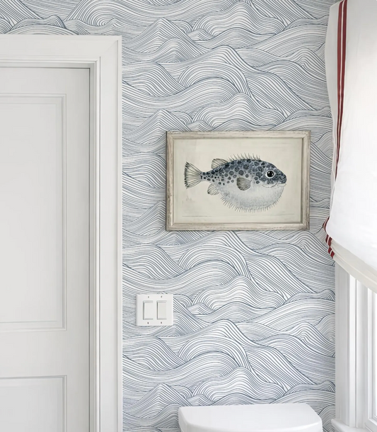 a bathroom with a framed illustration of a fish on the wall, a white door, and a white toilet.