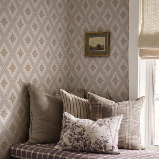 a cozy corner of a room with a patterned wallpaper, a window with a beige curtain, and a bed with a floral patterned pillow.