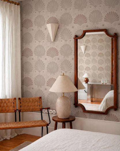 a cozy bedroom with a large mirror, a wooden chair, and a lamp on a small table. The walls are covered in a patterned wallpaper with a repeating design of seashells and stars.