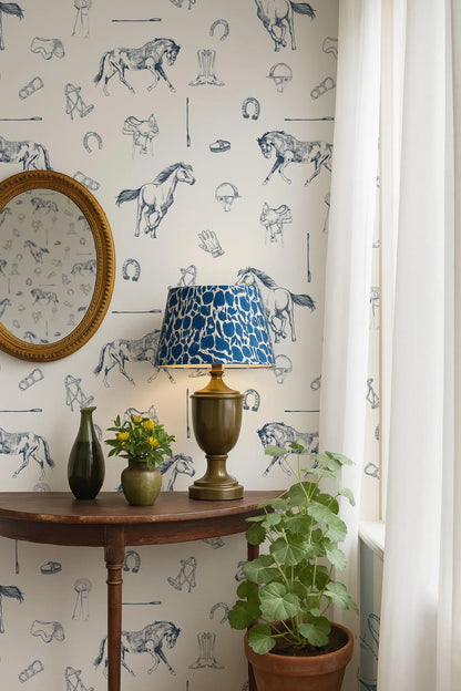 a room with a wooden table, a lamp with a blue and white patterned lampshade, a round mirror, a potted plant, and a vase with flowers. The wall behind the table has a wallpaper with various horse illustrations.
