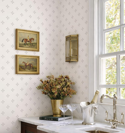 a cozy and elegant kitchen corner with a white marble countertop, a vase of flowers, a wine glass holder, and a book. The wall behind the countertop has a patterned wallpaper, and there are two framed paintings hanging on the wall.