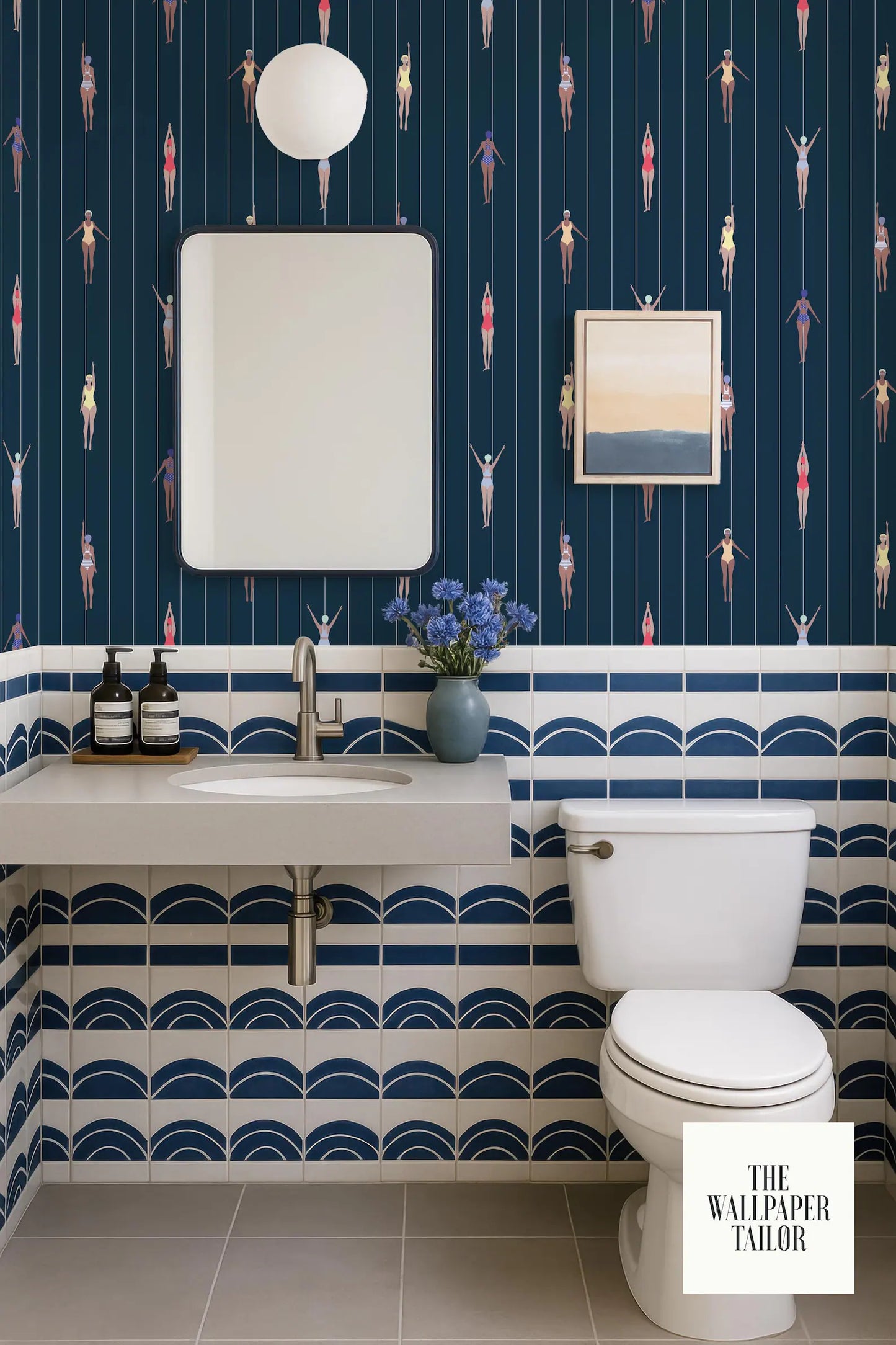 a bathroom with a blue and white color scheme, featuring a white sink, toilet, and a framed picture on the wall. The bathroom has a patterned tile design, and there is a vase of flowers on the counter.