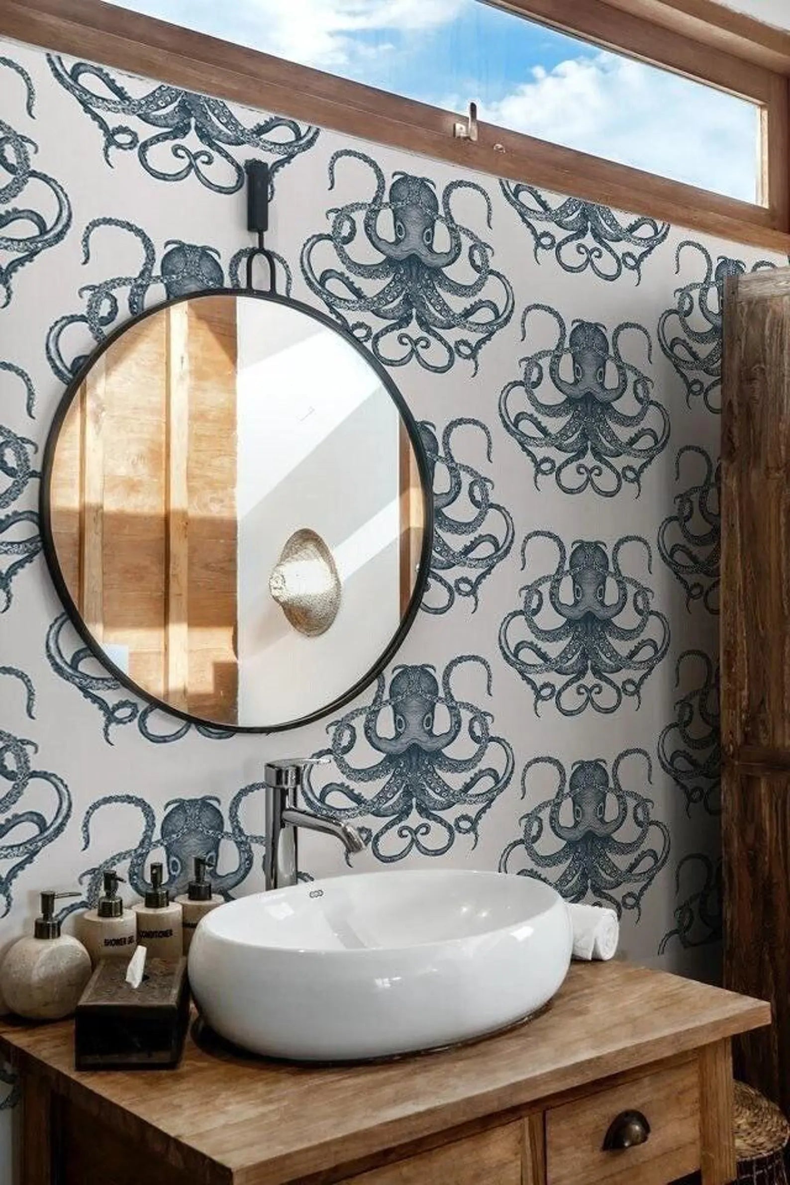 a bathroom with a round mirror, a white sink, and a wall with a repeating pattern of octopus designs.