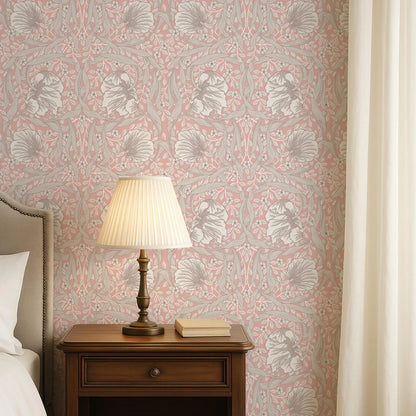 a bedroom setting with a wooden nightstand, a lamp, and a book. The wall behind the nightstand has a pink and white floral wallpaper.