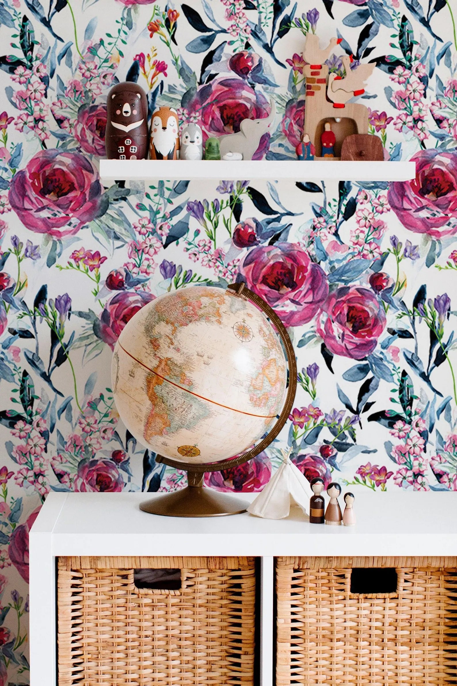 a shelf with a globe, figurines, and a wicker basket, set against a wall with a floral wallpaper.