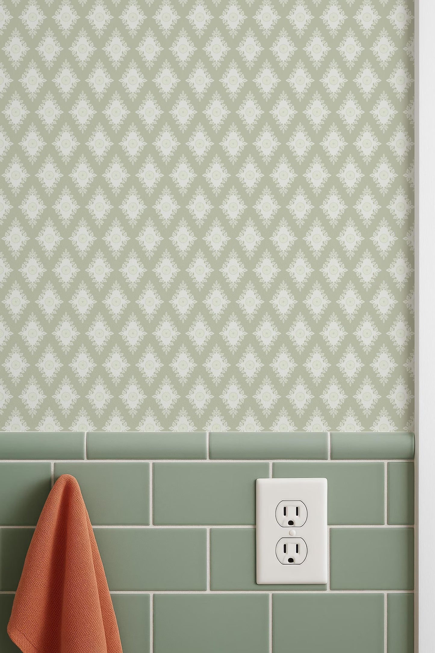 a wall with a patterned wallpaper and green subway tiles, with a white electrical outlet and a red towel hanging on the wall.
