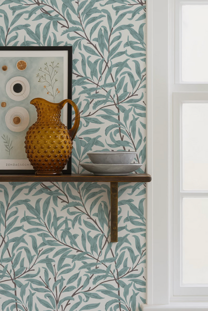 a shelf with a decorative vase, a bowl, and a picture frame, set against a wall with a leafy green and white patterned wallpaper.